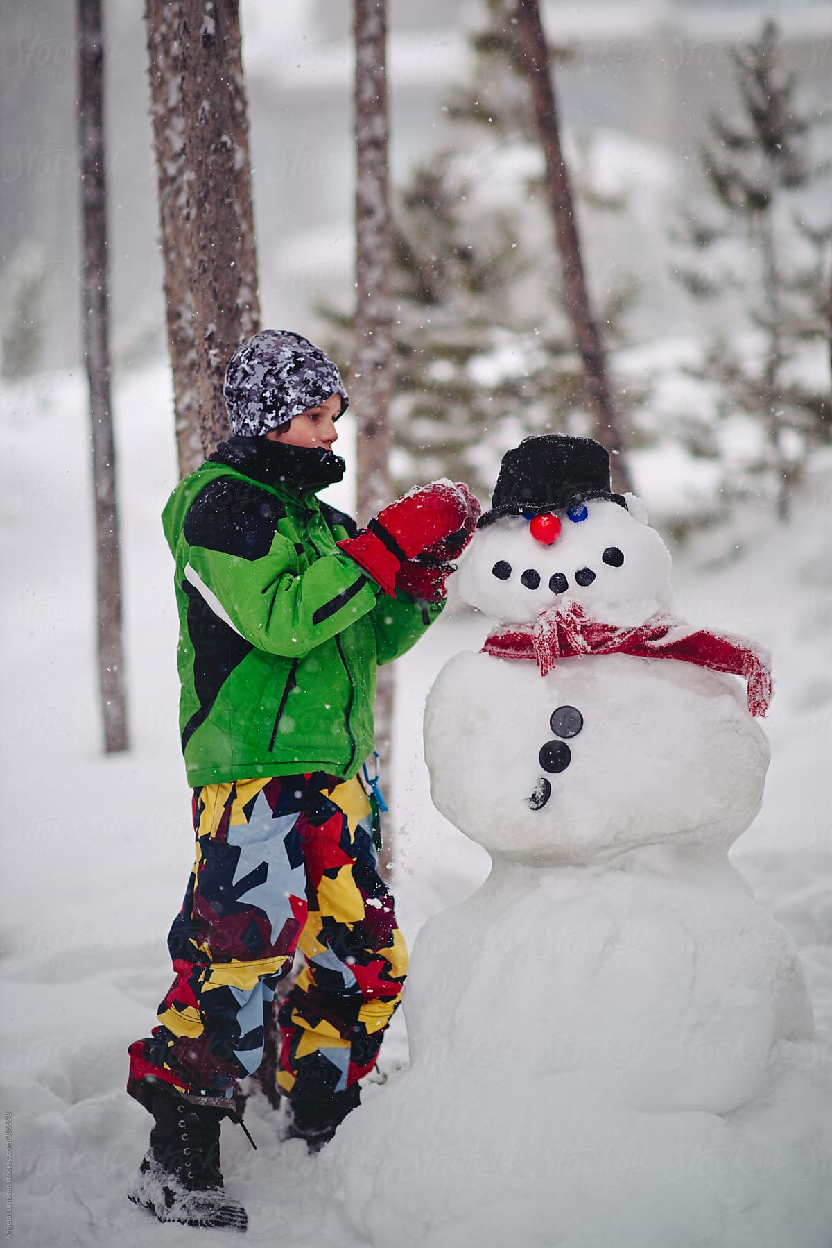 Boy putting finishing touches on a snowman on a snowy day