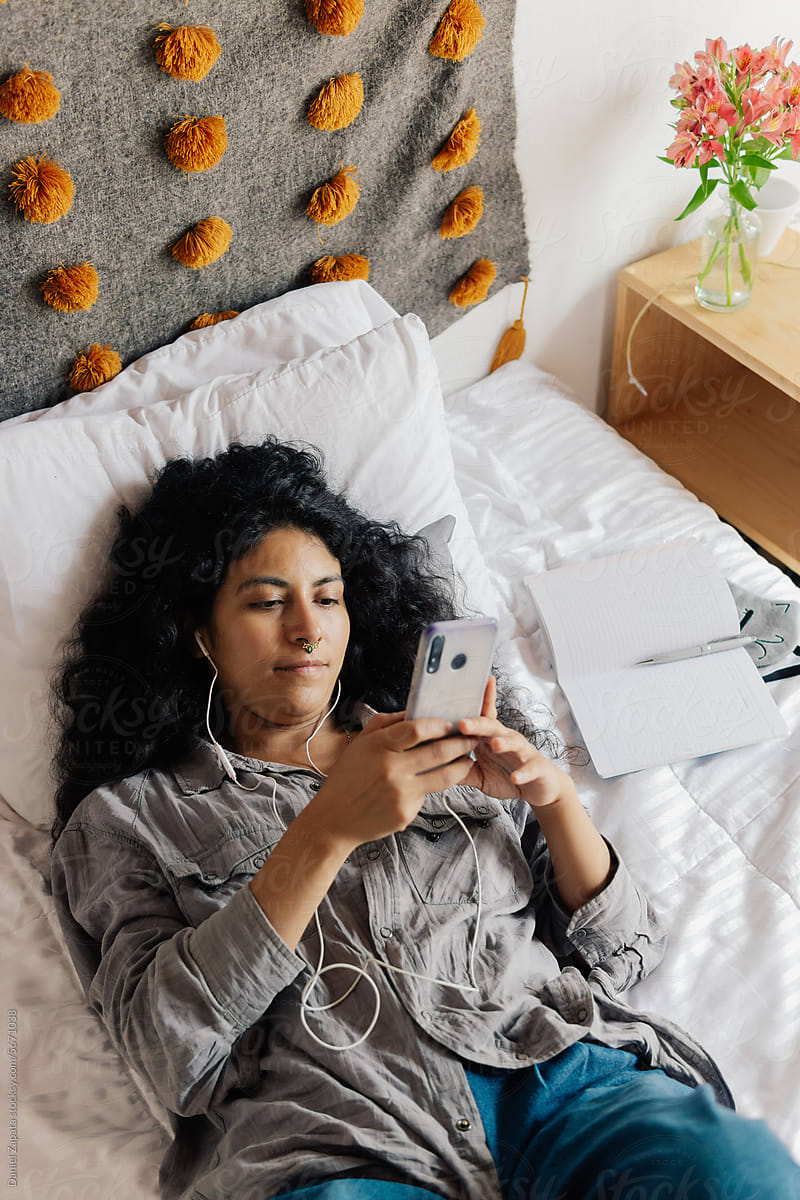 Woman lying in bed listening to music.