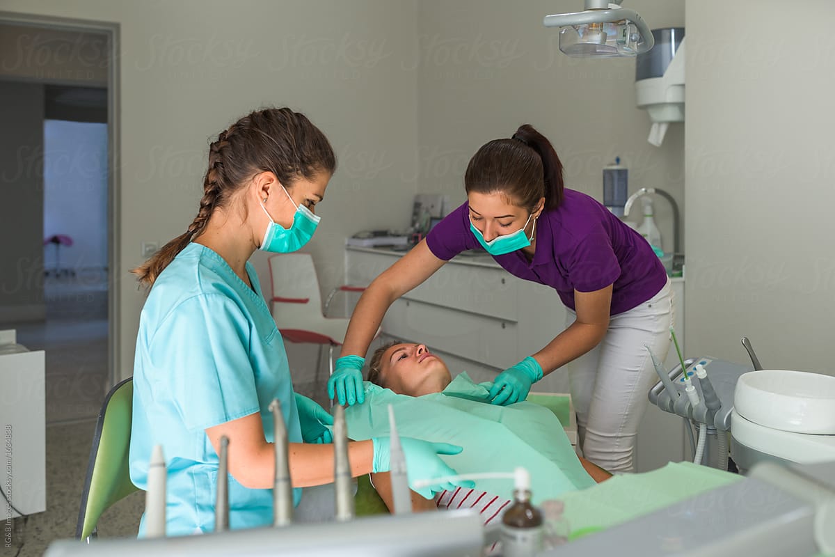 Orthodontist assisted by her nurse preparing patient for dental intervention