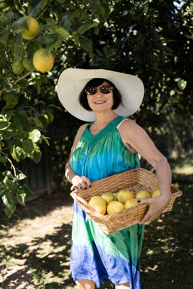 Senior woman holding basket with lemons.