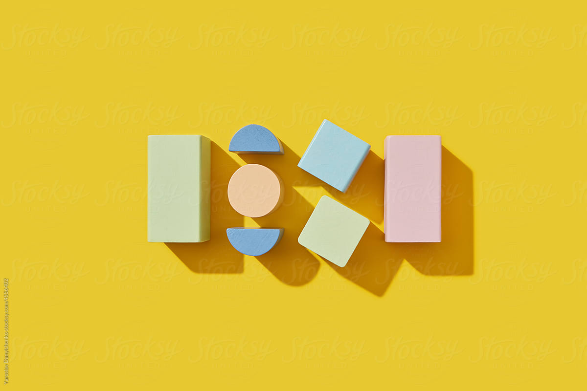 Wooden blocks of various shape and size on yellow background
