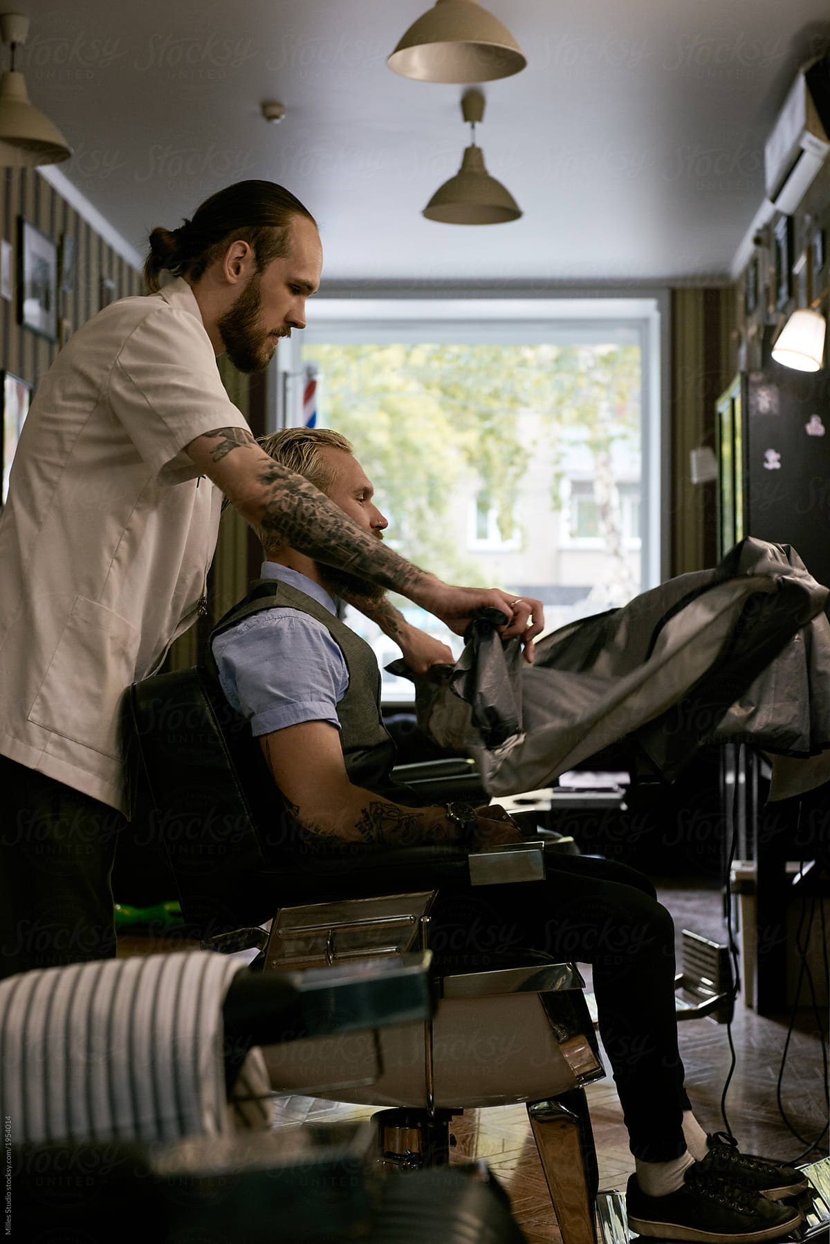 Barber putting protective cape on client