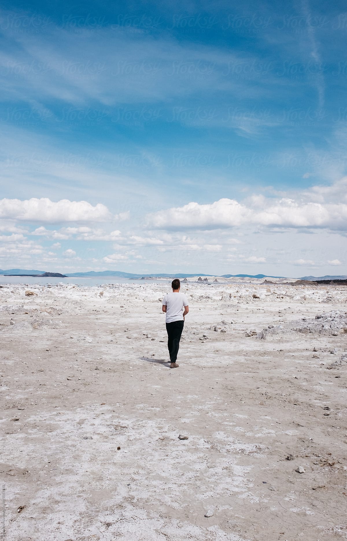 young man walks toward lake in white sand interesting landscape