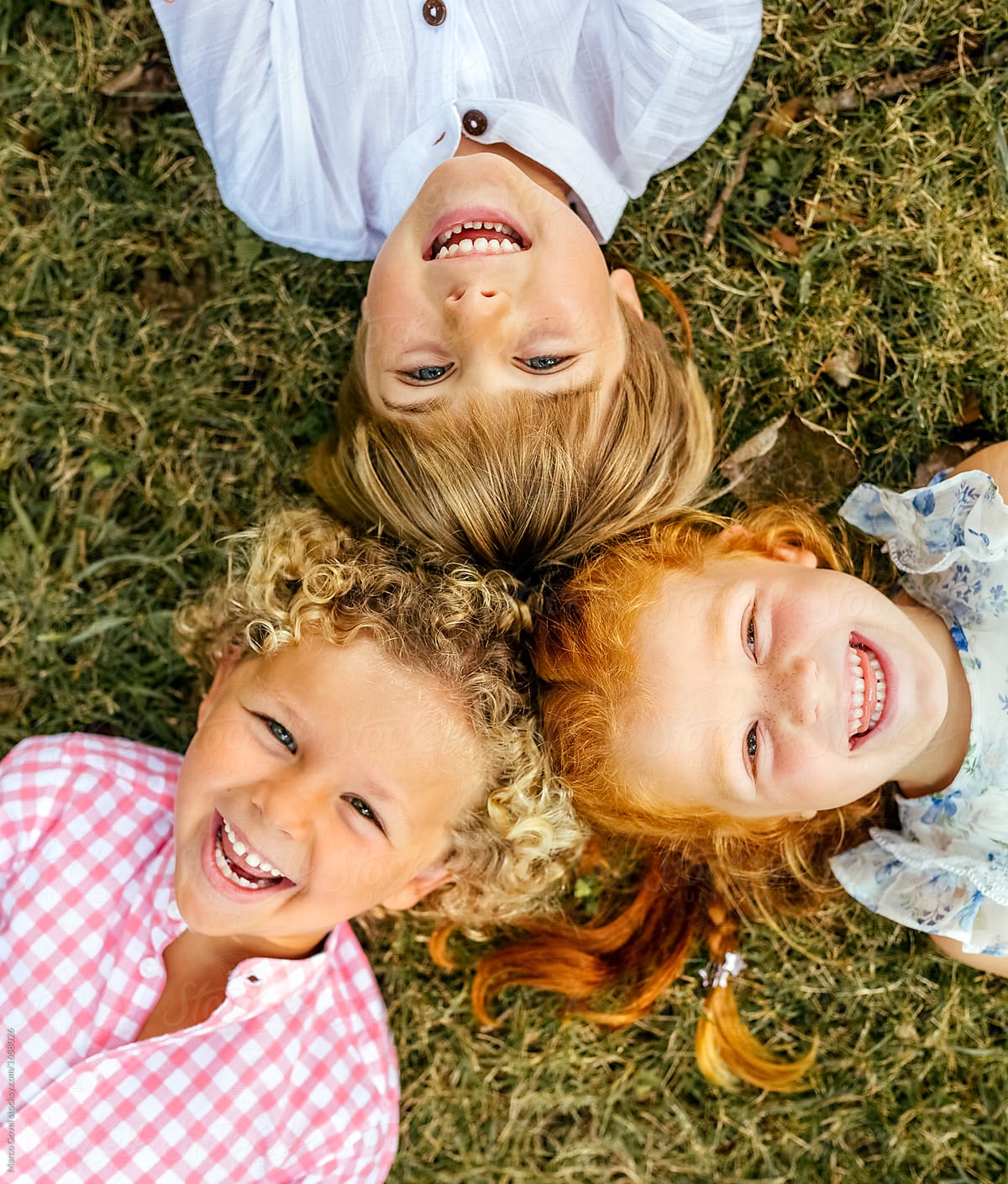 Three smiling children lying on the grass