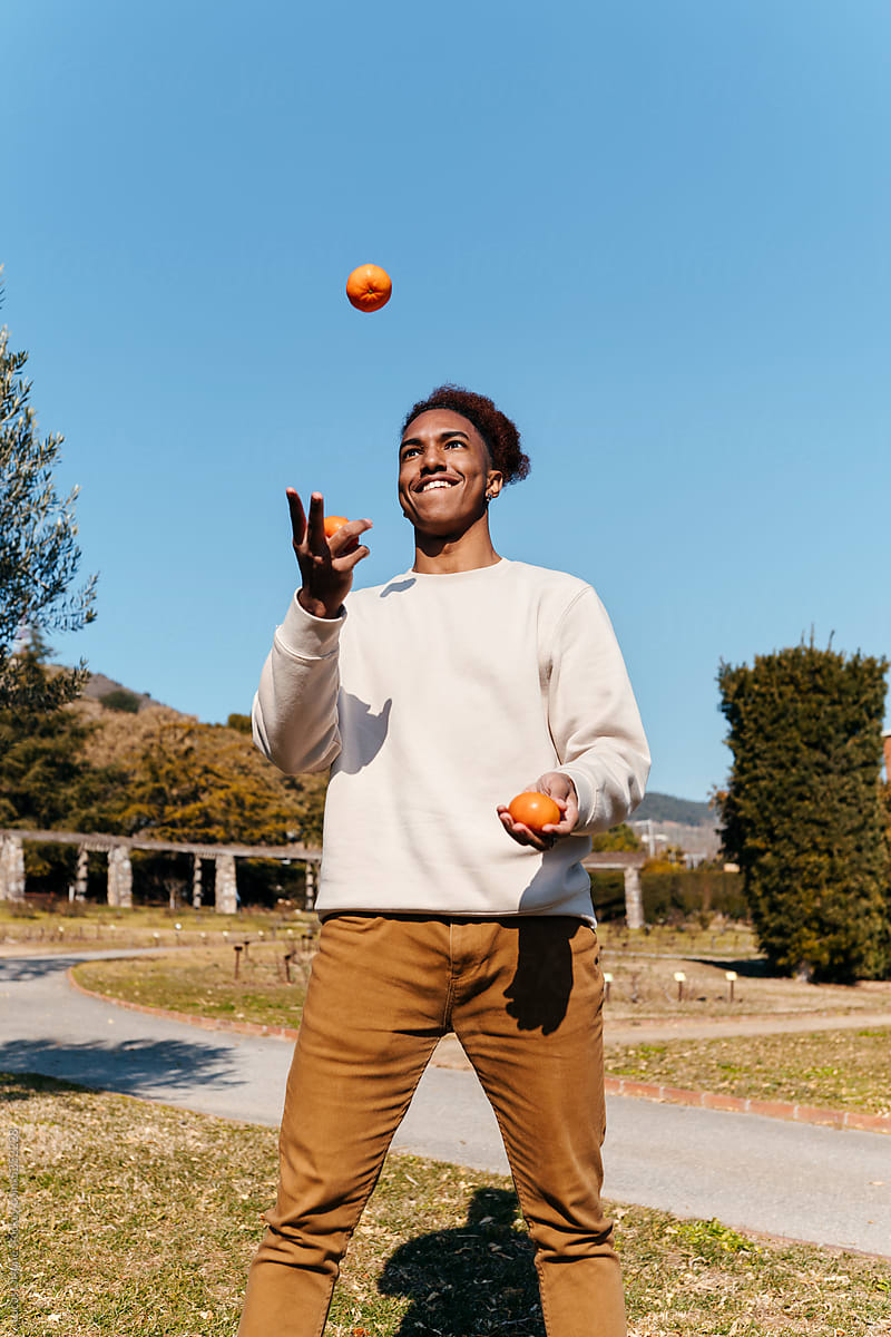 Black young man juggling with clementines