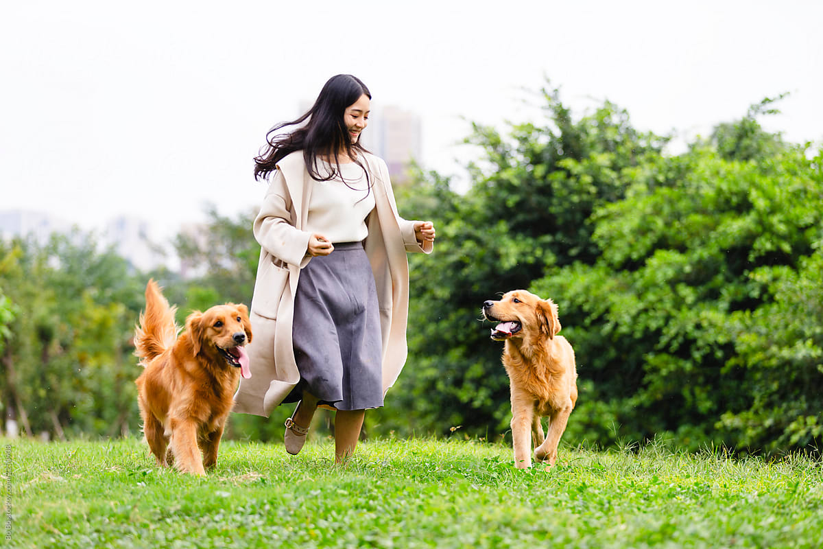 Happy young asianw woman walking with her two dog in the park
