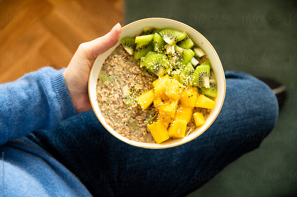 Woman holding healthy overnight oatmeal breakfast with fruit topping