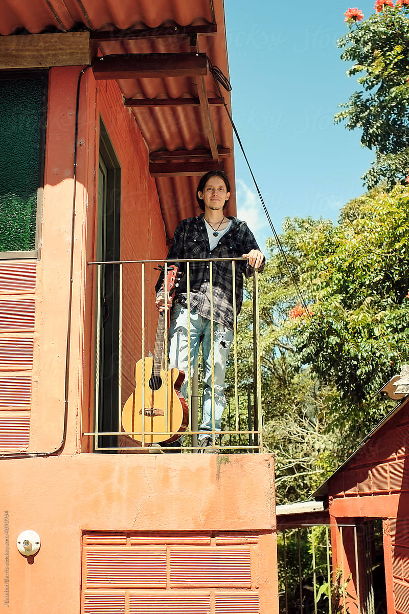 Musician with his guitar leaning on a balcony