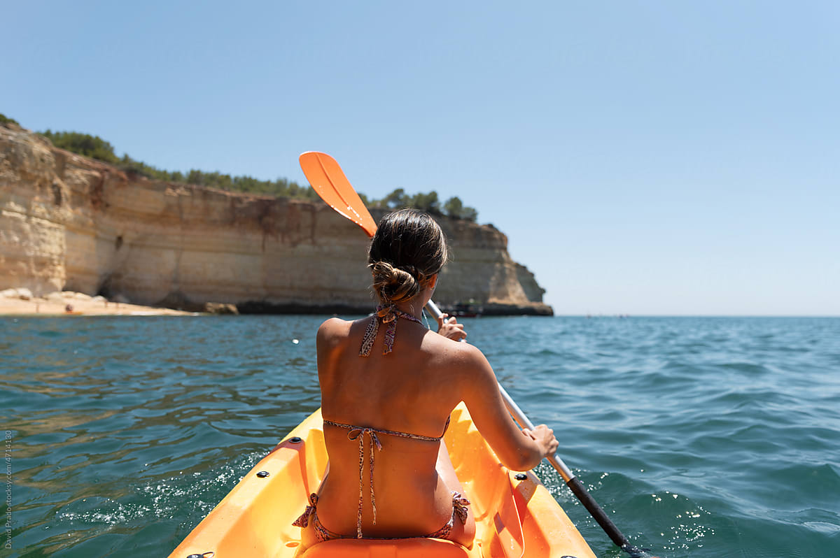 Woman in bikini sitting on kayak in sea