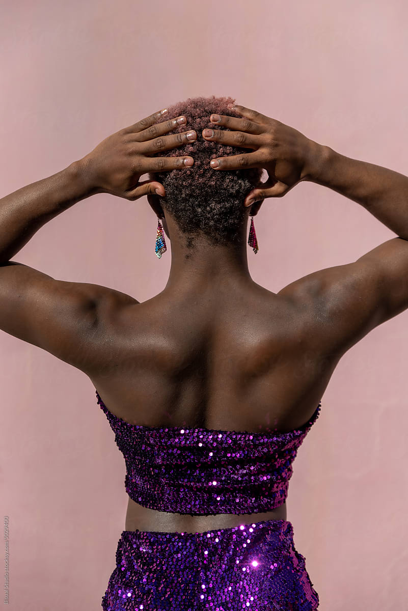 Transgender woman with sequined suit over pink wall
