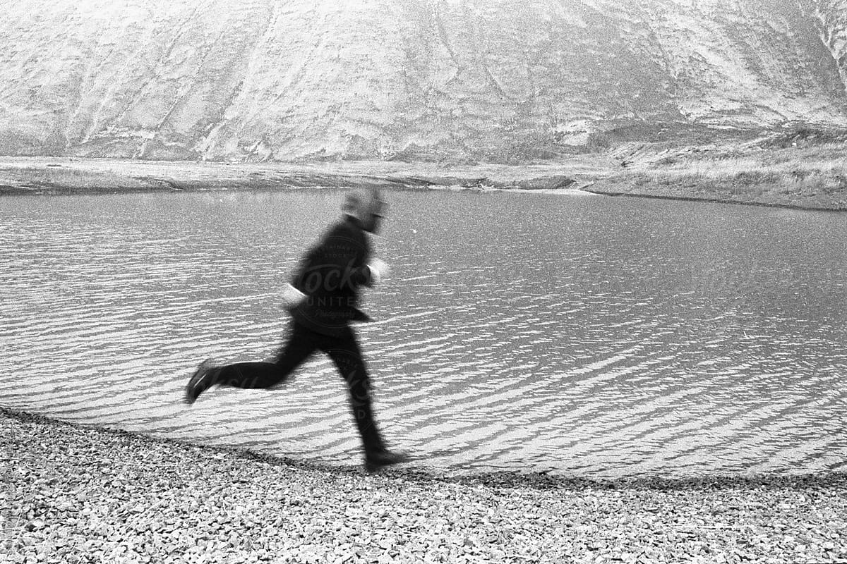 a masked man runs against the background of lake
