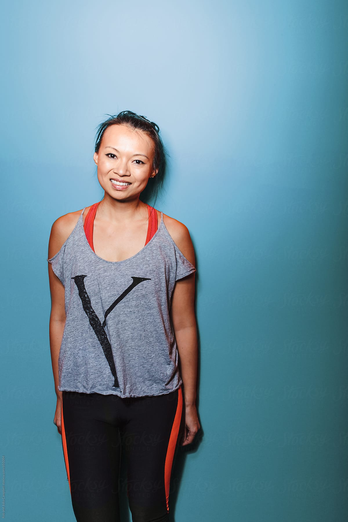 Happy asian woman smiling near blue wall - sweaty and smiling after hard workout