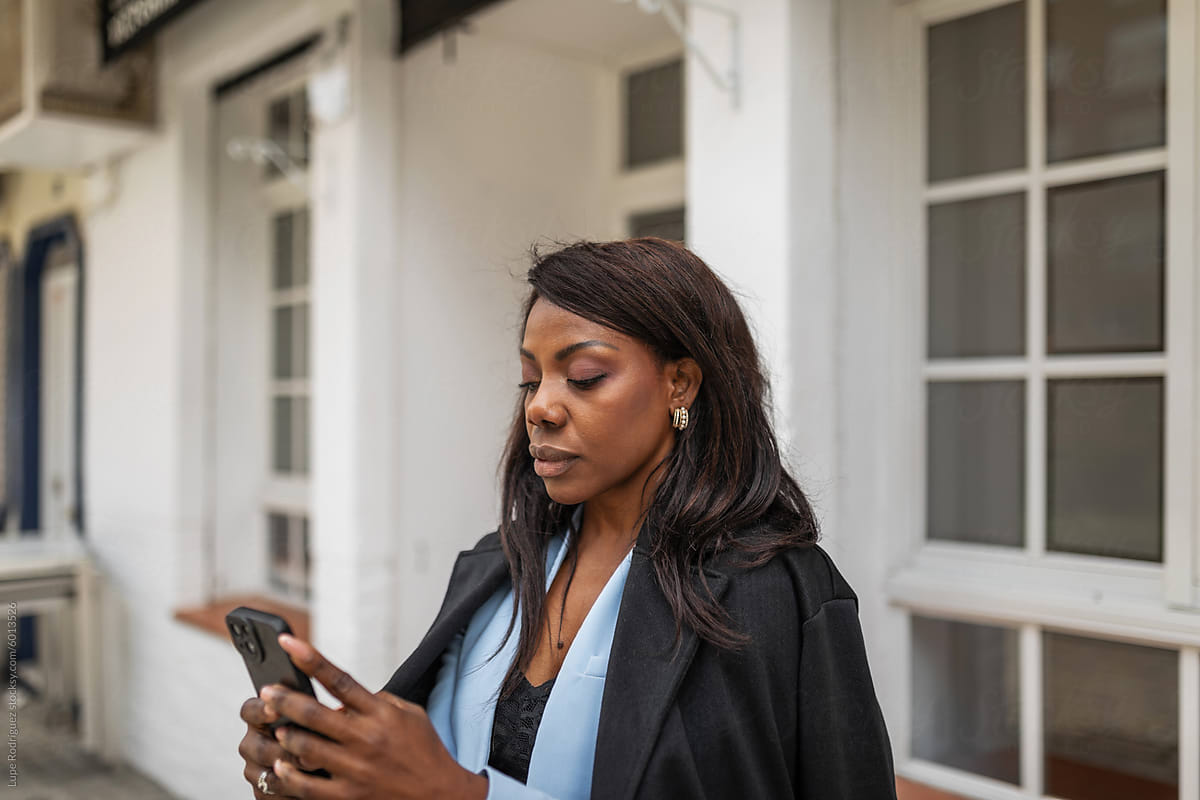 portrait of black woman with cell phone in front of a restaurant