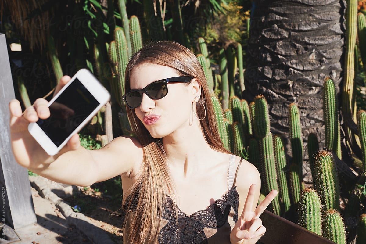 Girl taking selfie  against cactus