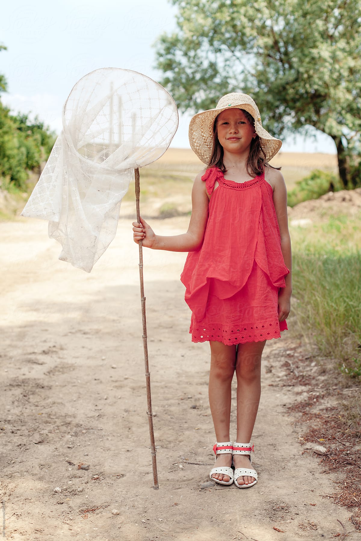 Little Girl With Red Dress Holding A Bug Catching Net by Stocksy