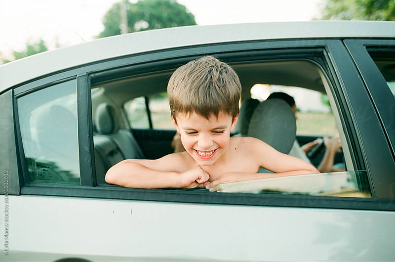 boy smiles out car window
