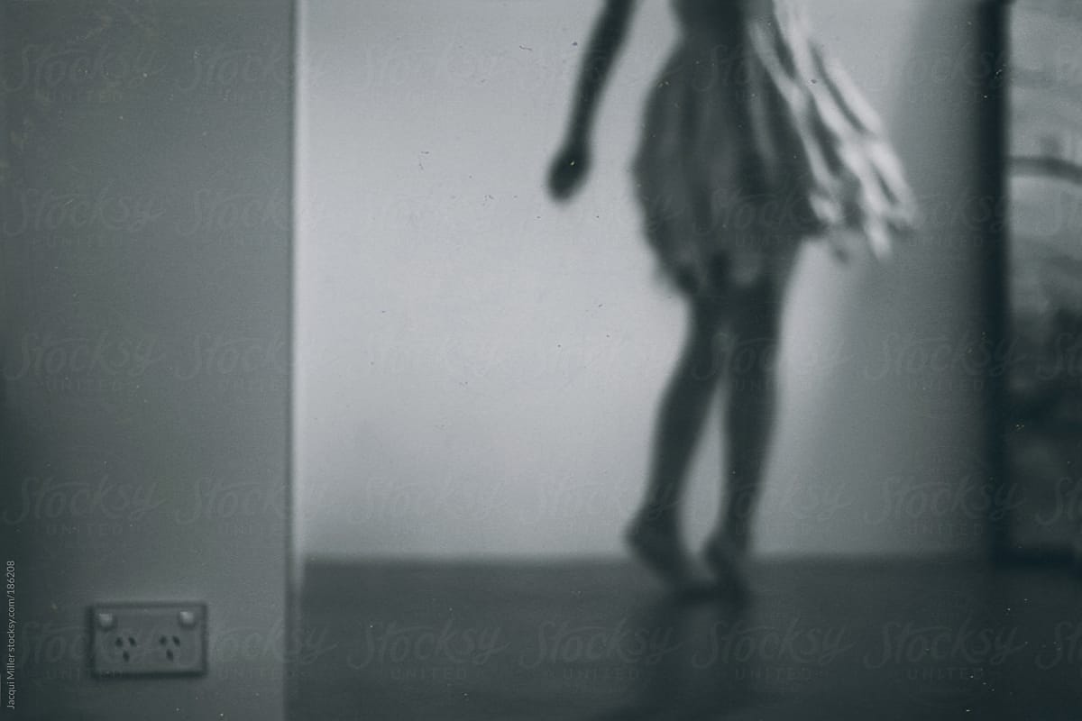Woman wearing a flowing skirt twirls alone in her home