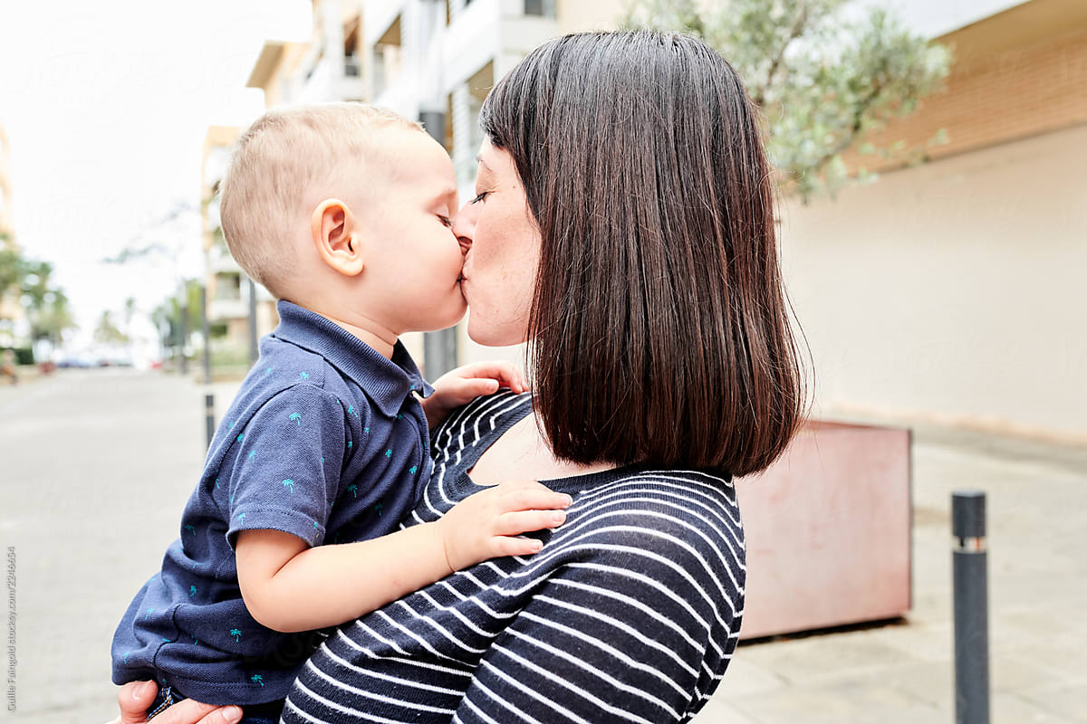 Loving woman kissing infant boy in cheek