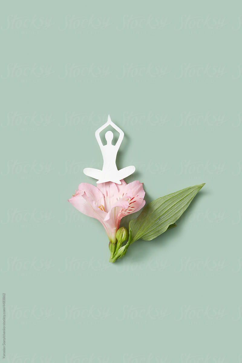 Papercraft figure of woman practicing yoga on pink flower