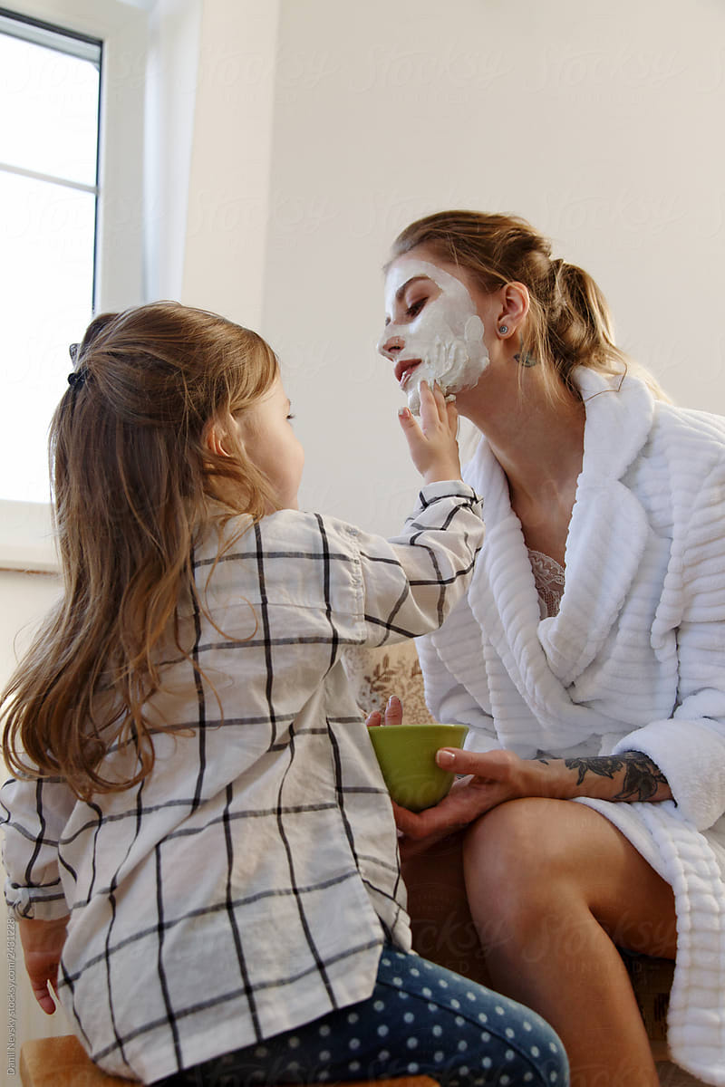 Girl smearing mask on jaw of mother