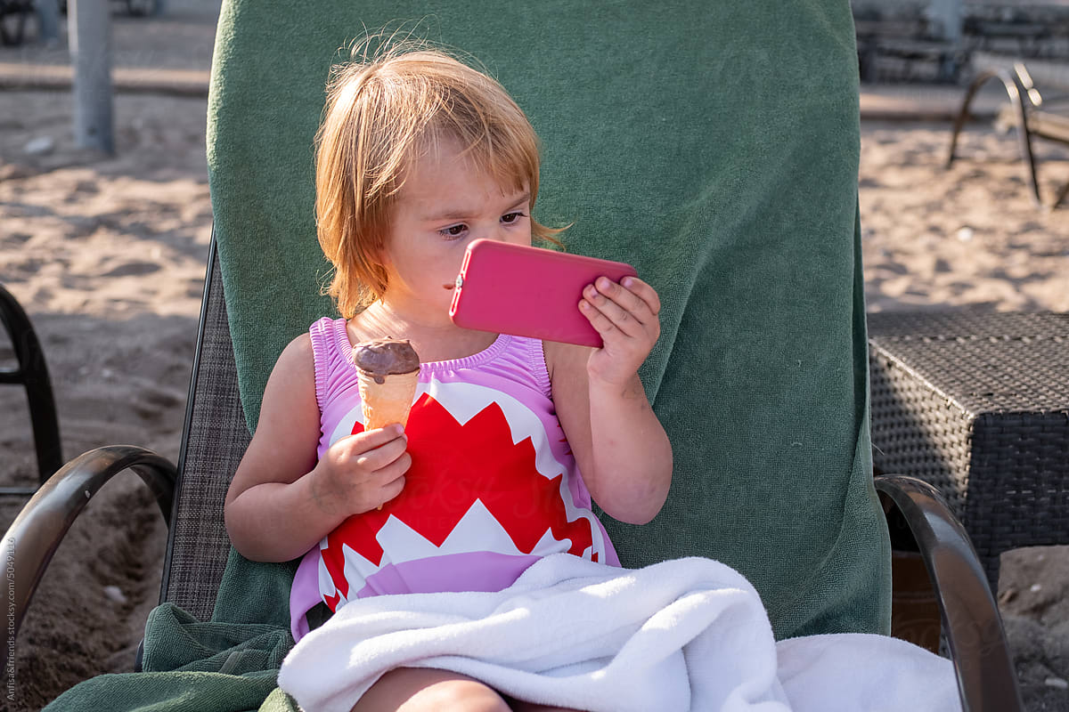 little girl using tablet eating chocolate ice cream
