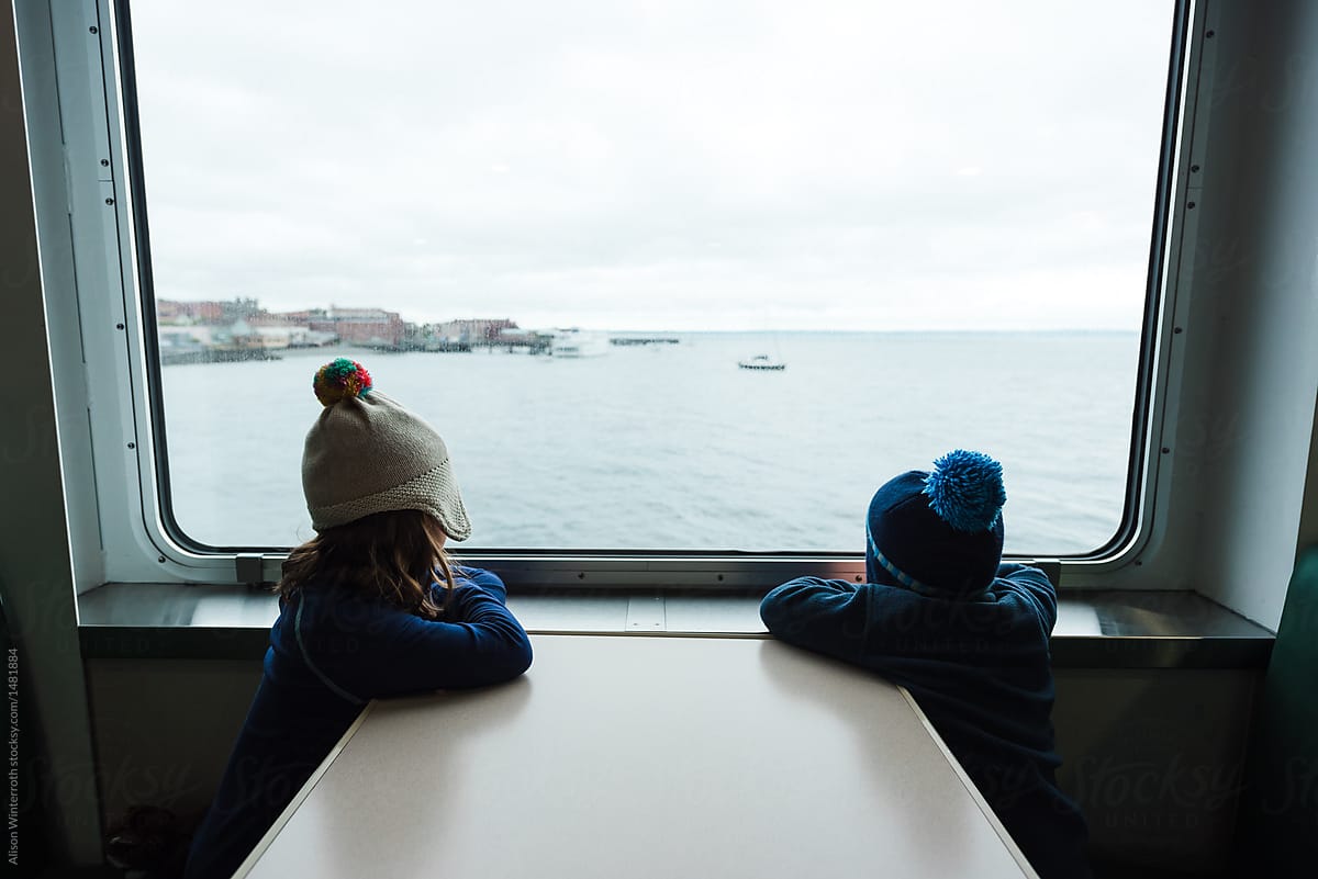 A Boy And Girl Look Out The Window Of A Ferry