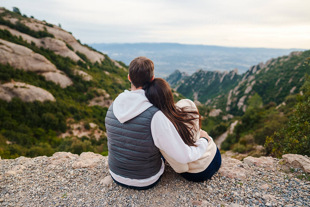 Rear view of hugging couple in love on top of mountain