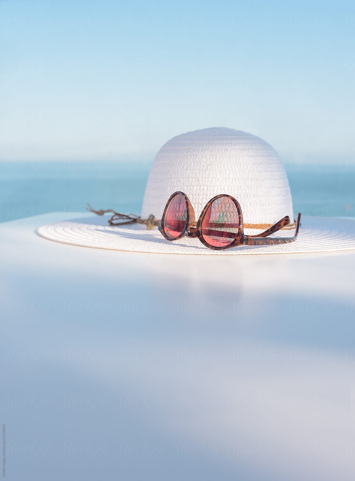 Close up on white straw hat and brown retro sunglasses