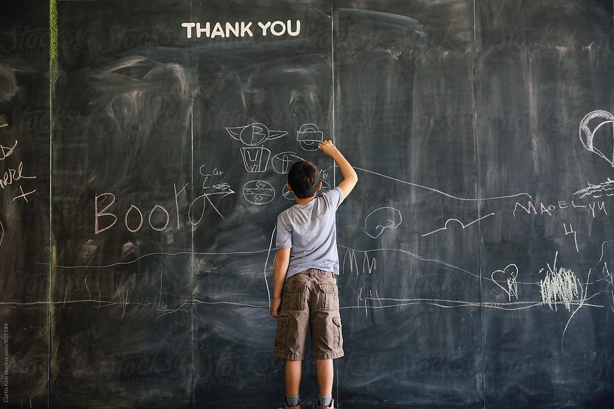 Boy drawing on a large chalkboard paint wall