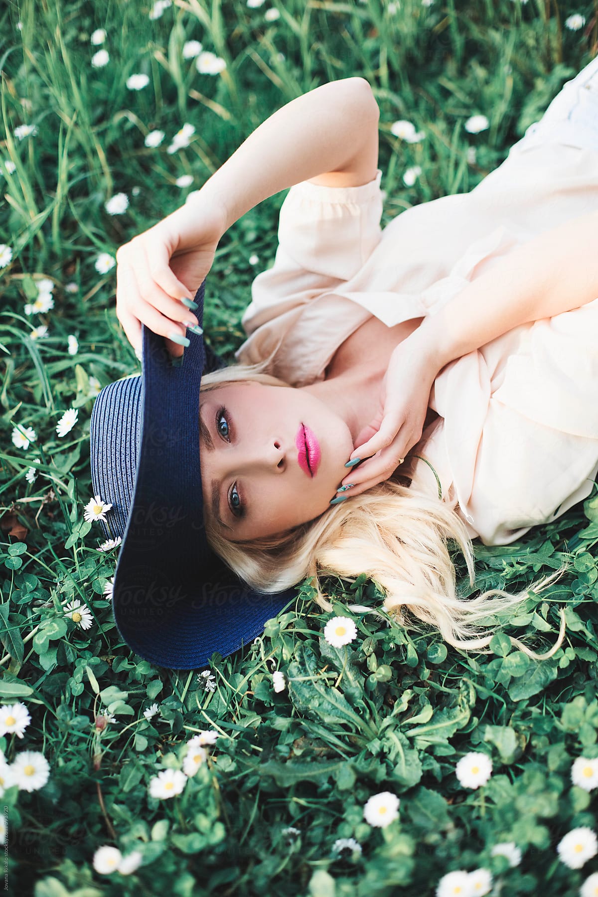 Beautiful Young Woman Lying On Grass Wearing A Summer Hat By Stocksy Contributor Jovana