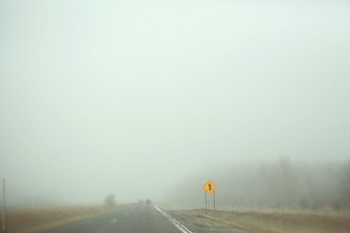 A Merge Sign On A Highway On A Foggy Morning