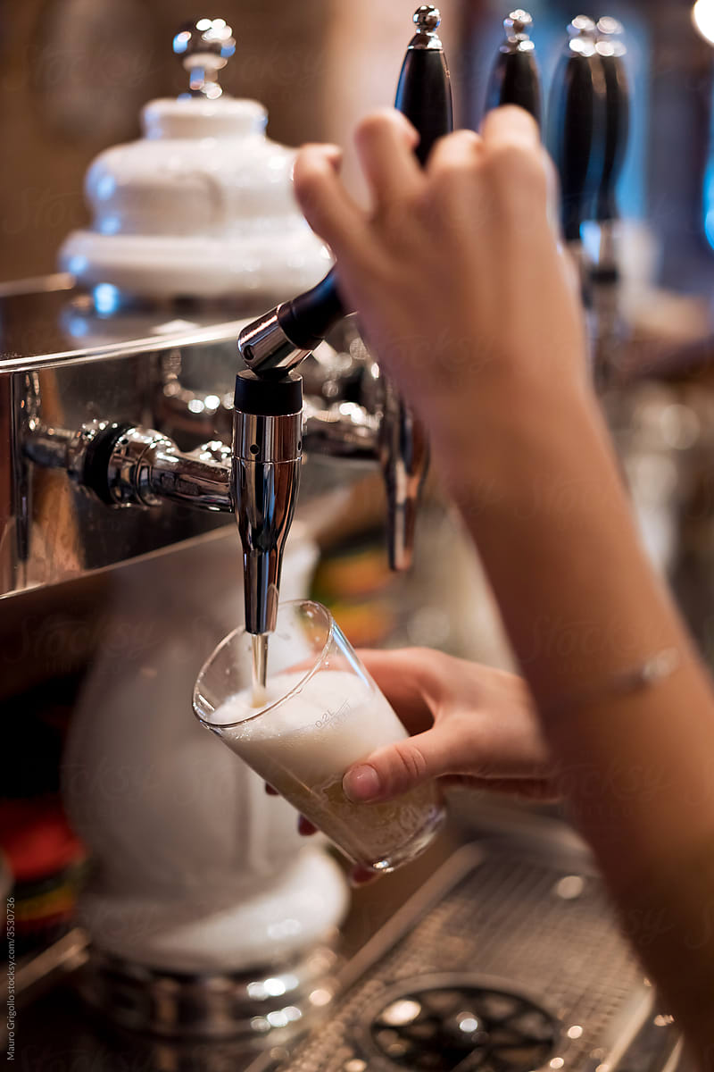 Woman bartender preparing a beer
