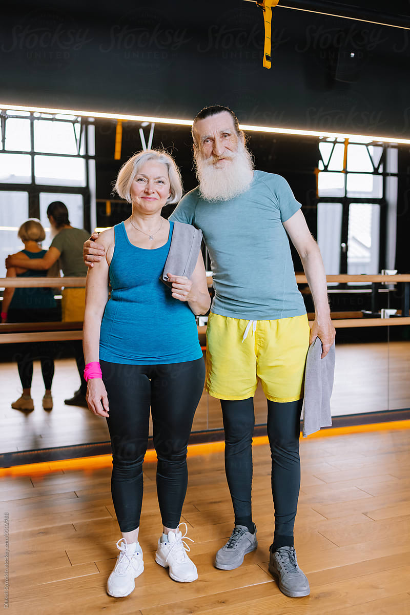 Boomer couple. Gym interior. After workout. Mirror wall. Cheerful grin