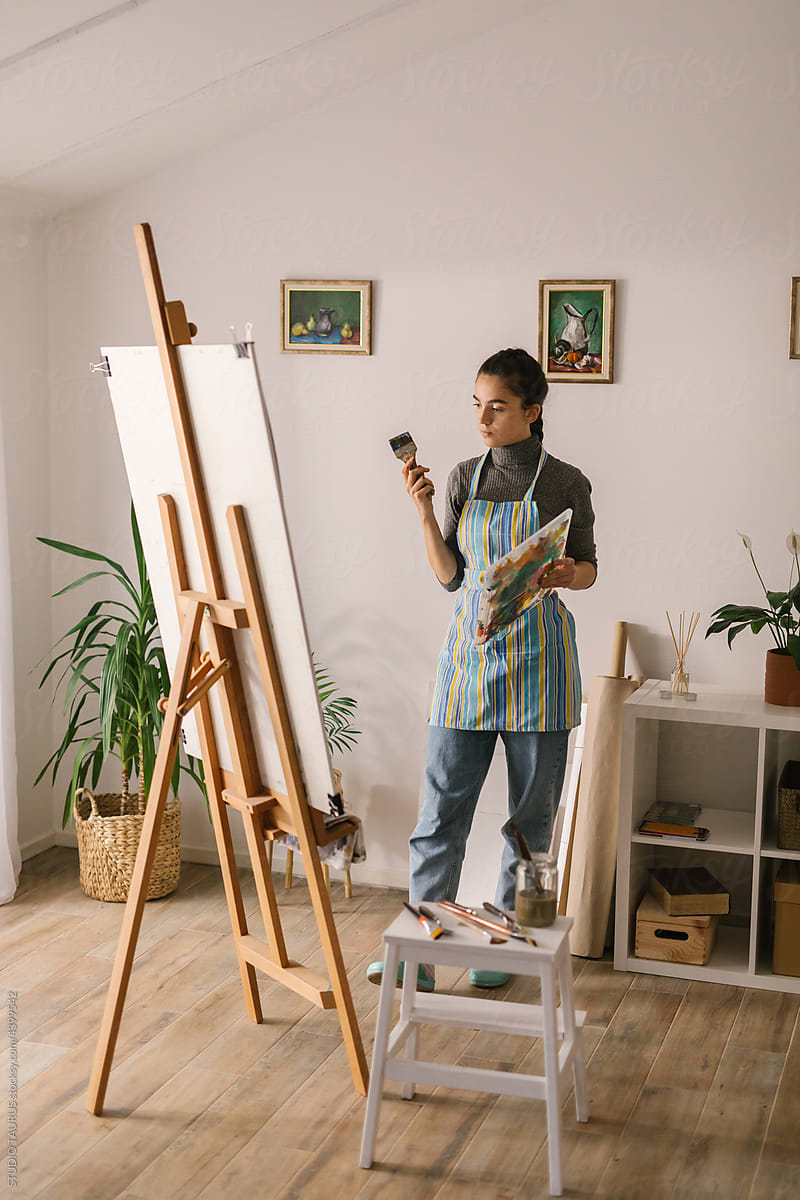 Female artist observing her painting in art studio