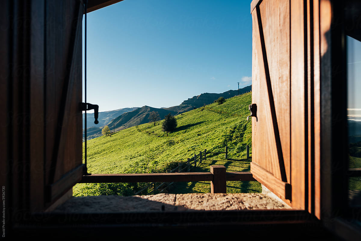 scenery of grassy mountain valley from wooden window