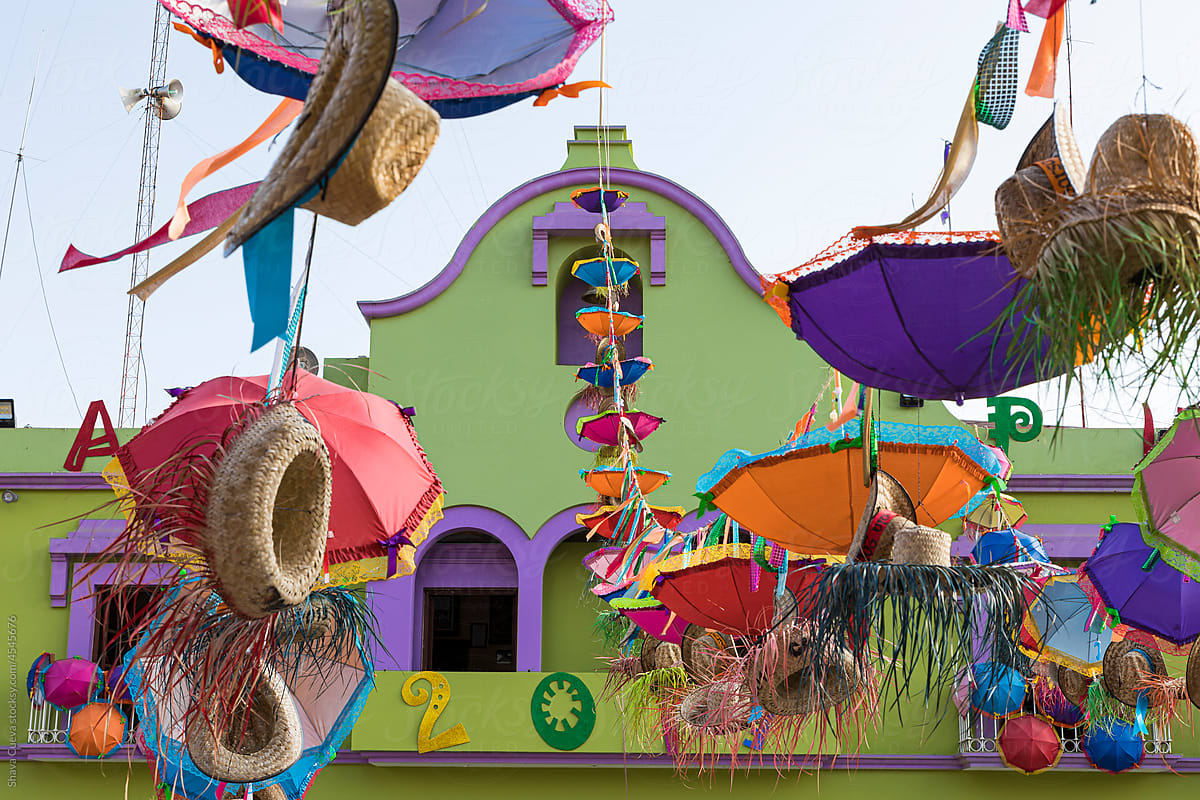 Hats and umbrellas hung for carnival in front of a colorful building