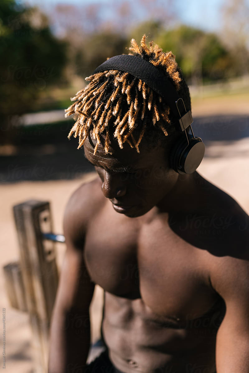 Shirtless African male in headphones on sports ground