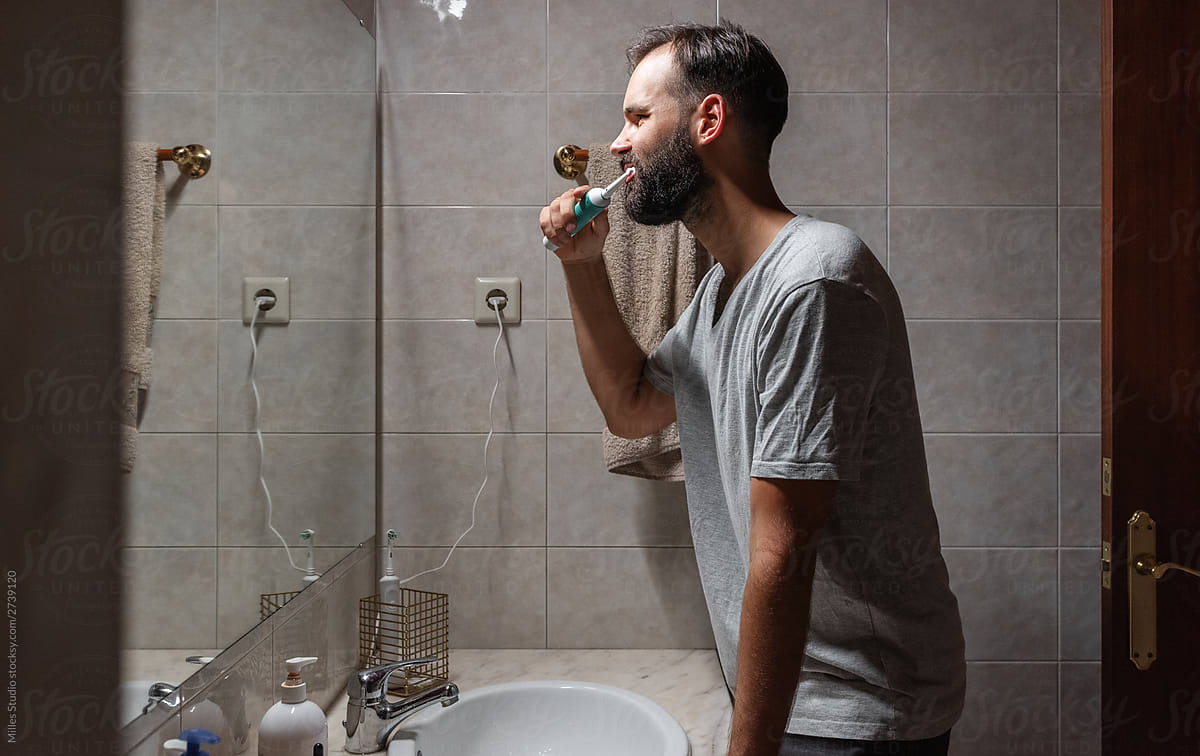 Bearded man brushing teeth in bathroom