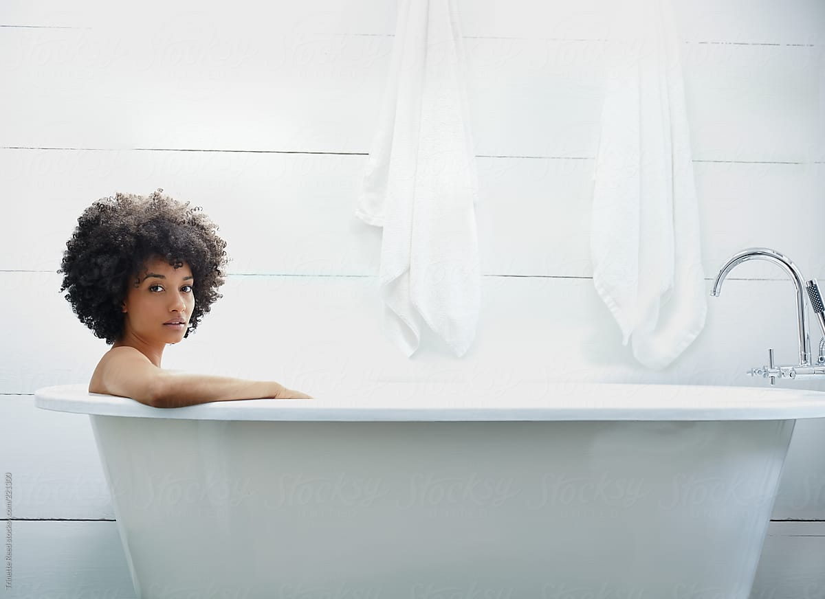 Portrait of woman relaxing and taking a bath in freestanding bathtub in far...