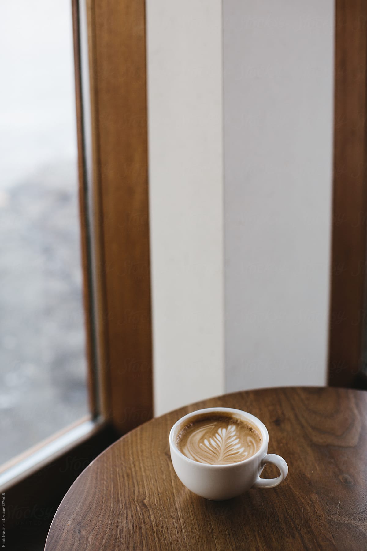 latte on dark wood table in corner of coffee shop