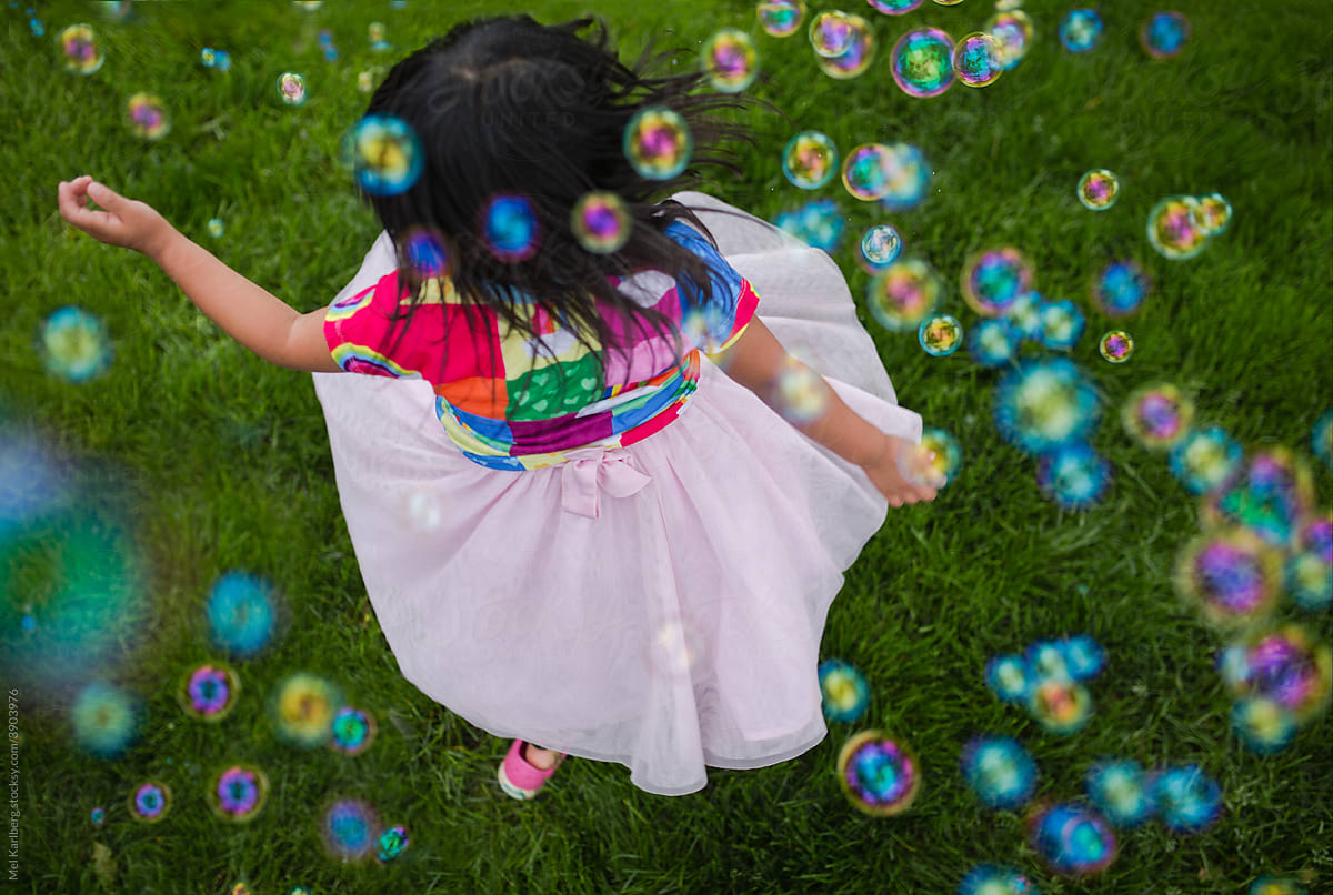 Young girl twirling in bubbles