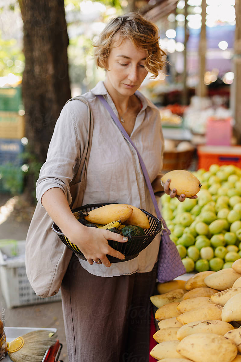 Woman with reusable bag buying fresh fruits at stall