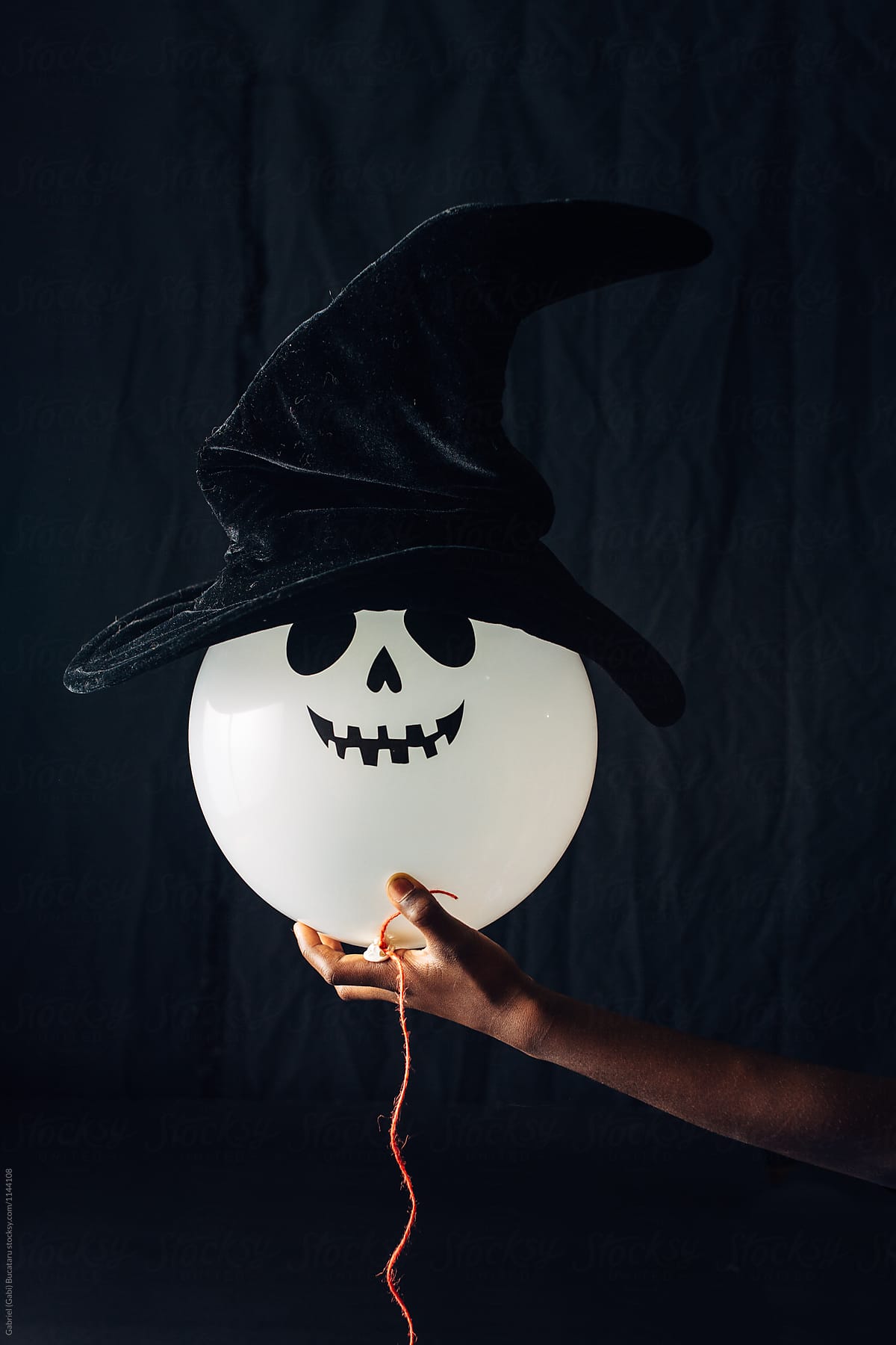 Ghost Halloween balloon with wich hat held in child\'s hand