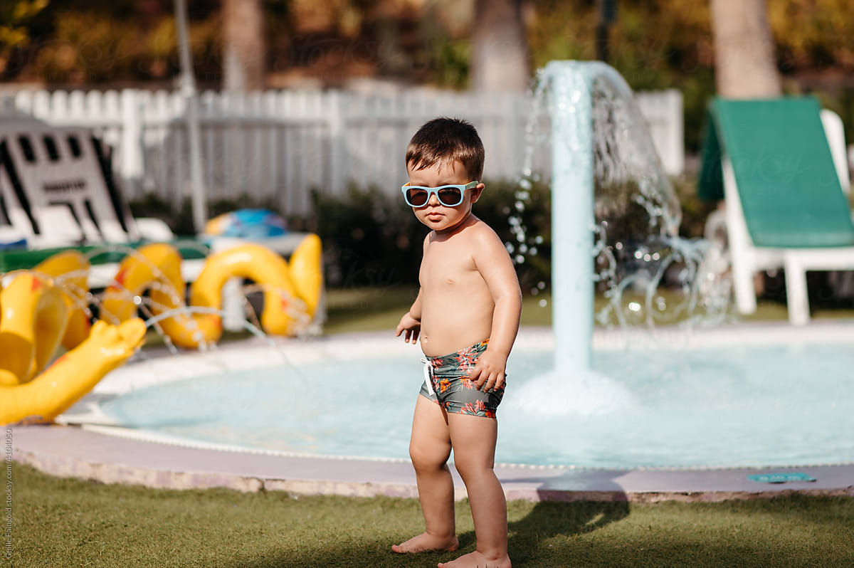 Cool toddler in sunglasses by pool.