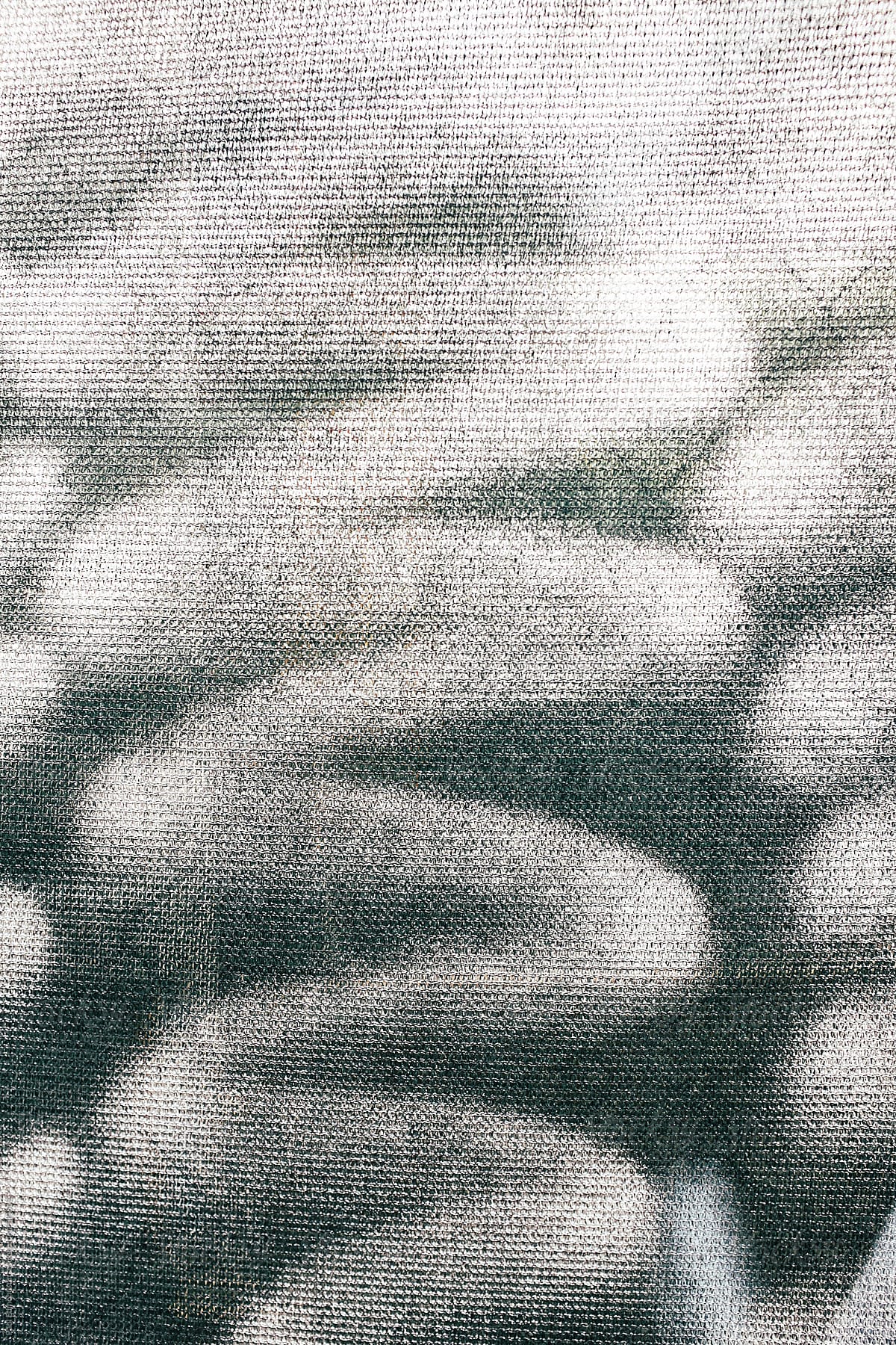 White spray paint markings covering graffiti tags on industrial fabric, close up
