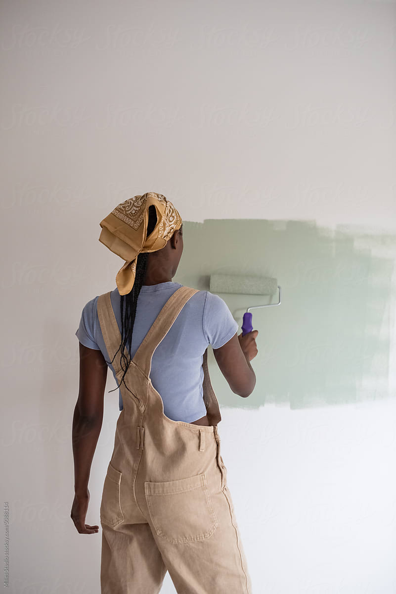 Black female repainting wall at home