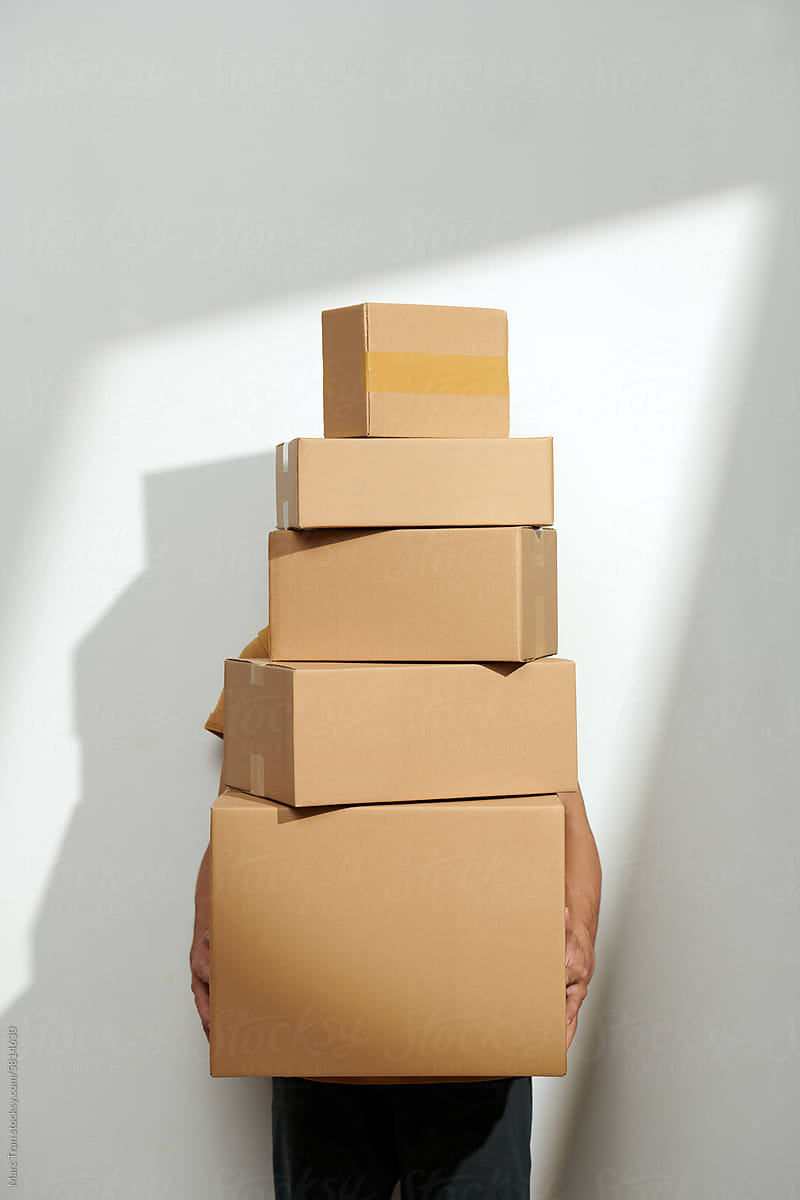 Man with moving boxes on white wall with sunlight