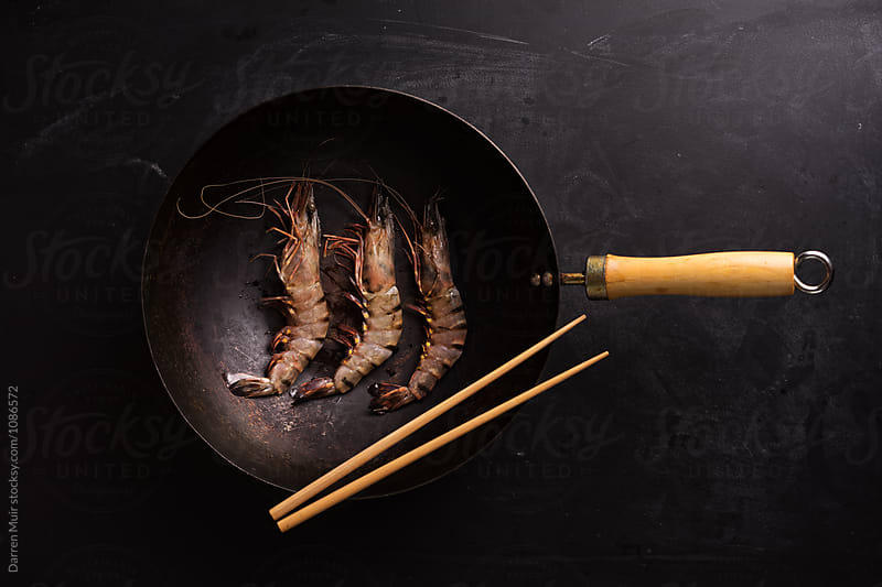 Black tiger prawns in a wok on a dark background.