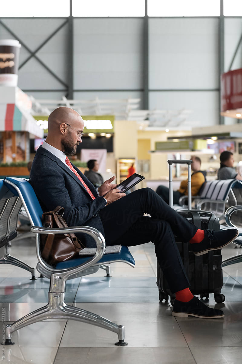 Bearded businessman relaxing with tablet in airport