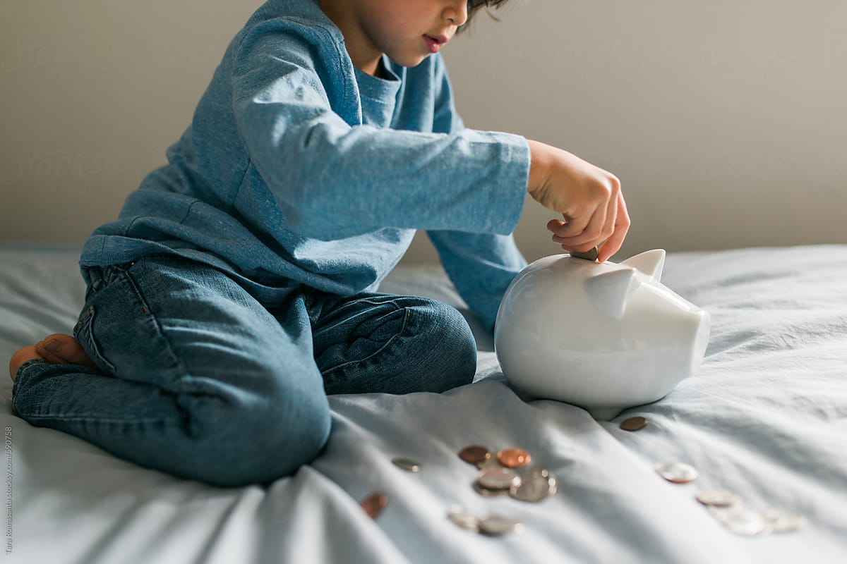 child places coins in a piggy bank